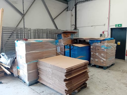 PACKING Stacks of cardboard boxes and pallets in a warehouse setting.